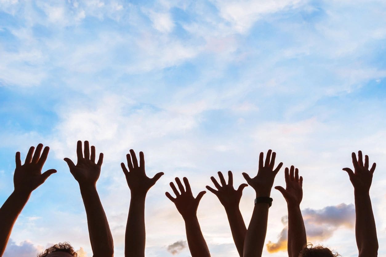 A group of people raising their hands in the air.